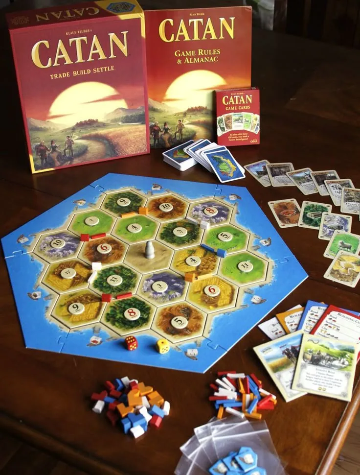 Partida de Catan con el tablero hexagonal, cartas de recursos y piezas de colores