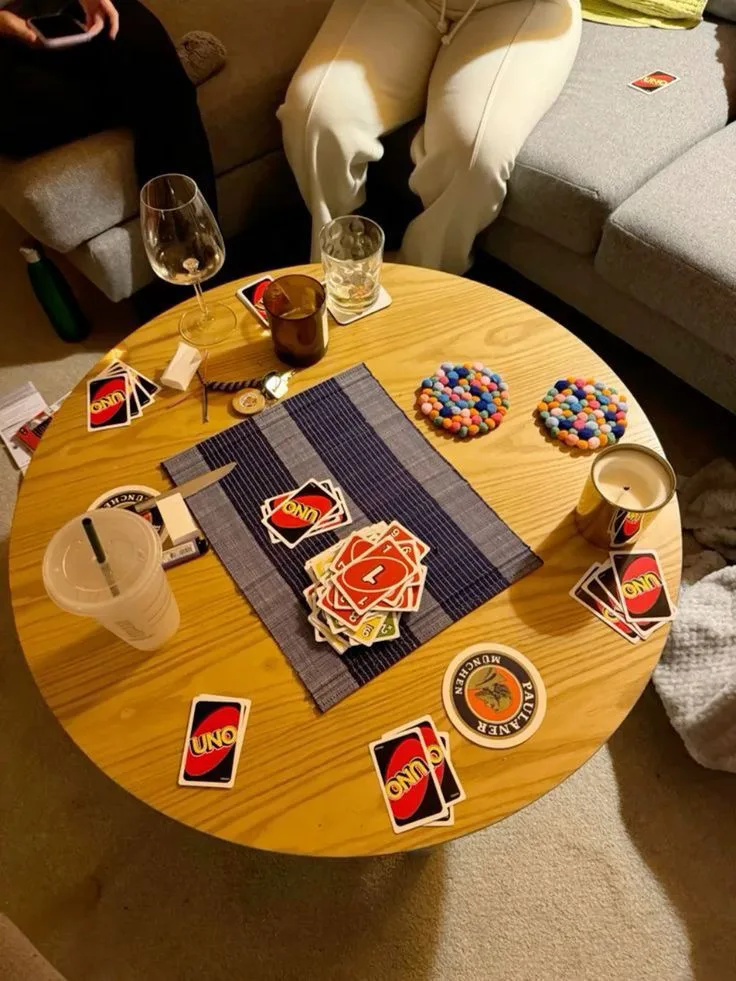 Mesa redonda con cartas de UNO durante una partida entre amigos